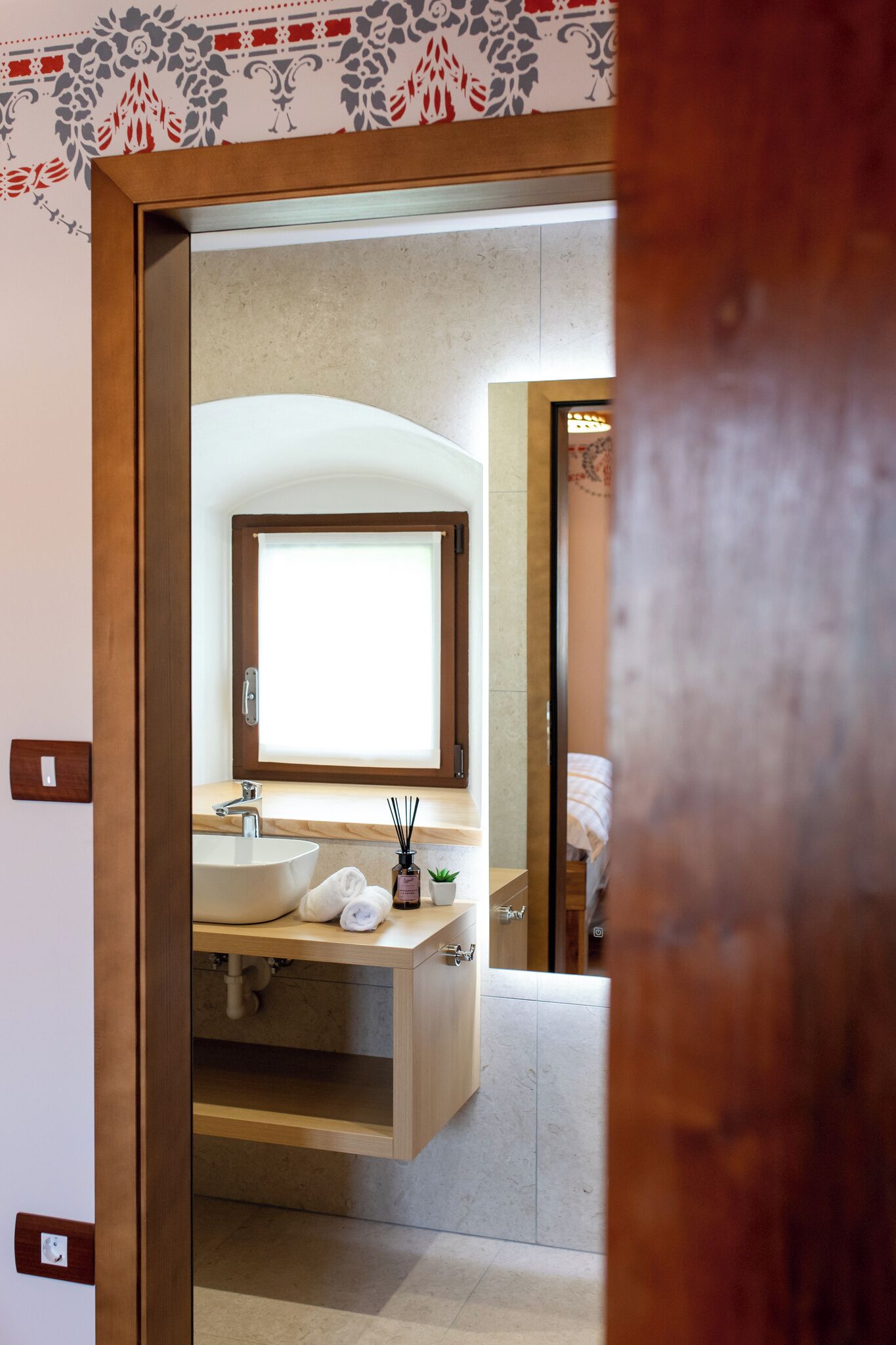 A modern bathroom with a large mirror, a sink, and a window.