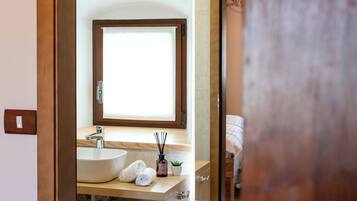 A modern bathroom with a large mirror, a sink, and a window.