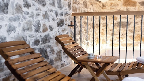 Ein Holz-Loungebereich mit Steinwänden und einem Balkongeländer.