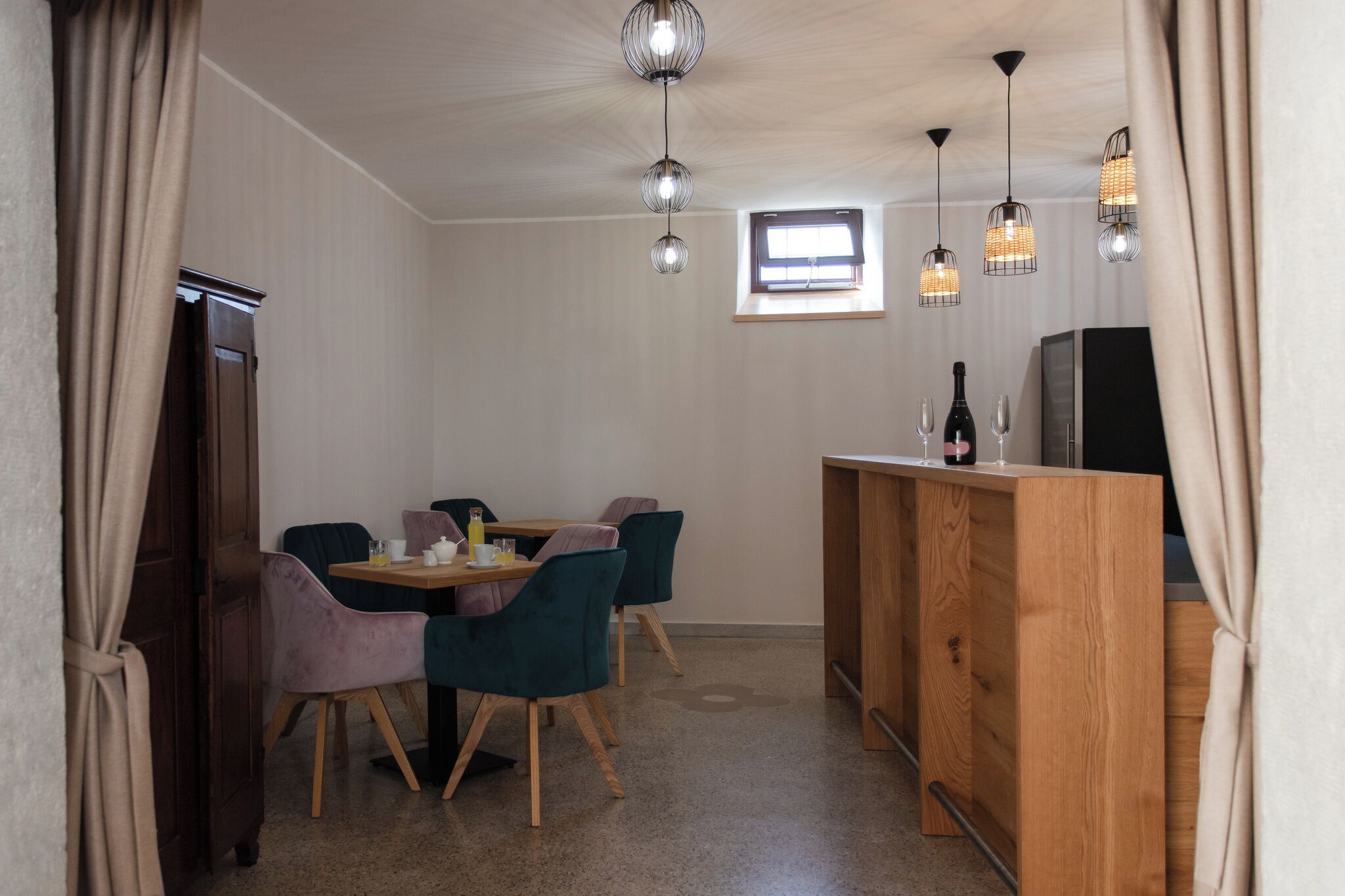 A compact room with a dining table, chairs, a wooden counter, and pendant lights.