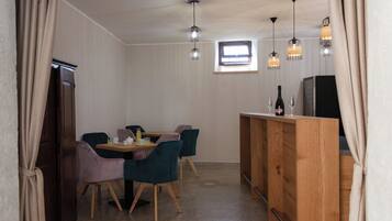 Une pièce de taille modeste comprenant une table à manger, des chaises, un comptoir en bois et des luminaires suspendus.