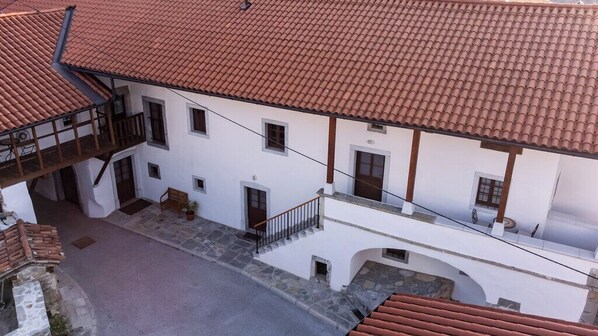 A white building with a red-tiled roof, multiple windows, and a staircase leading to an upper floor. - Wellba Boutique Hotel (Ajdovšcina)