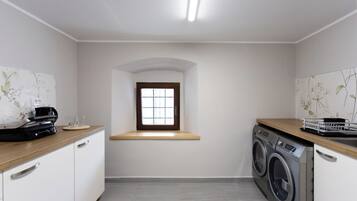 Une buanderie équipée d’un lave-linge, d’un sèche-linge, d’une machine à café et d’une petite fenêtre.