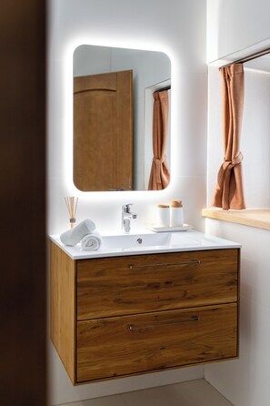 A modern bathroom with a white sink, wooden vanity, and a mirror with a lighted frame. - Wellba Boutique Hotel (Ajdovšcina)