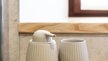 Una bandeja con dos tazas blancas de cerámica y un recipiente blanco de cerámica sobre una mesa de madera.