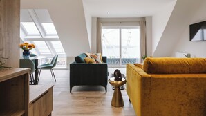 A modern loft apartment with a high ceiling, skylights, a dining area, a living room with a yellow sofa, and a large window with a city view. - VISIT THE LOOKOUT AND EXPERIENCE THE ATLANTIC OCEAN AT ITS BEST. (Portrush)