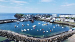 A harbor with numerous boats docked, a rocky breakwater, and buildings along the shore. - VISIT THE LOOKOUT AND EXPERIENCE THE ATLANTIC OCEAN AT ITS BEST. (Portrush)