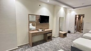 Una habitación de hotel con cama, escritorio con espejo, televisor y armario.