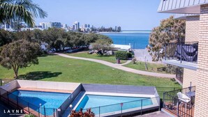 Una zona de piscina con vistas al océano y al horizonte de la ciudad.