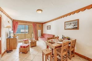 A cozy room with a wooden dining table set for a meal, a sofa, and a small cabinet. - Fitness, swimming pool, sauna, hammam, balcony, parking, tv, 58m², Champagny-en-Vanoise (Champagny-en-Vanoise)