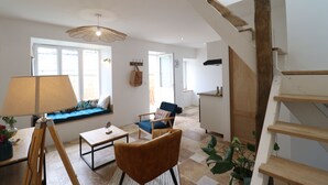 Un vaste espace de vie comprenant un canapé, un fauteuil, une lampe et un escalier.