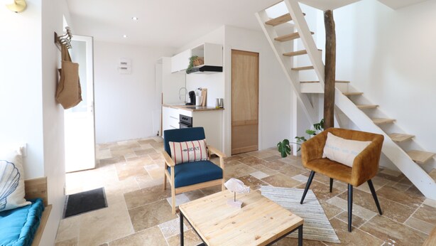 Un salon moderne avec un escalier, un coin repas et une cuisine.