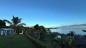 A coastal view with a small blue house, palm trees, and a clear sky. - Oceanfront Luxury Villa with Infinity Pool and Private Beach (Nosy Be)