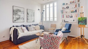 A modern living room with a sofa, armchairs, a coffee table, and a bookshelf.
