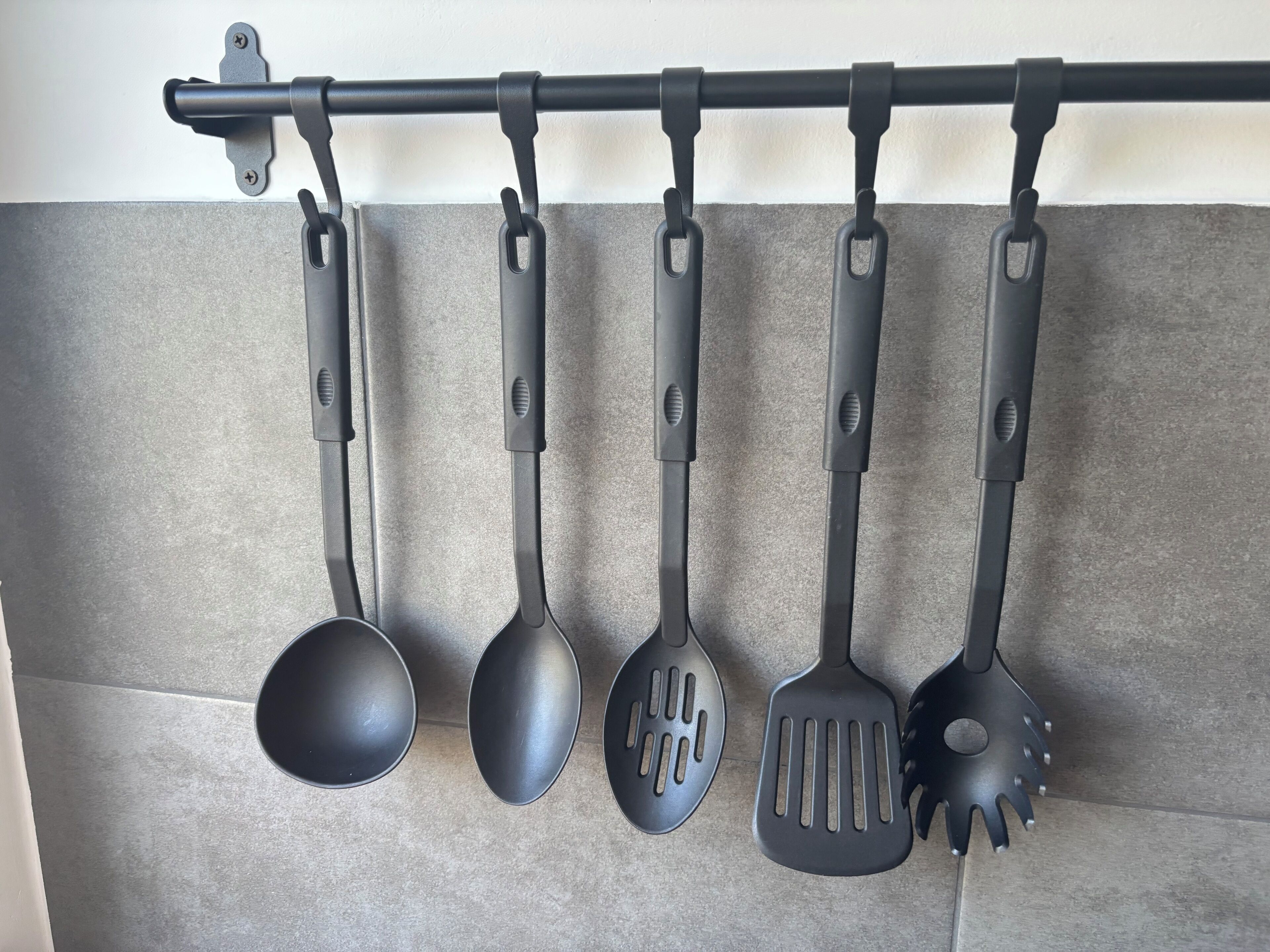 Un porte-ustensiles de cuisine contenant cinq ustensiles noirs.