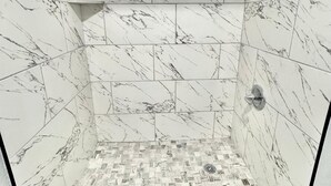 A shower with marble tiles and a mosaic floor. - Welcome Motel (Killeen)