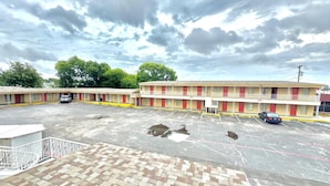 A motel with a parking lot and a brick walkway. - Welcome Motel (Killeen)