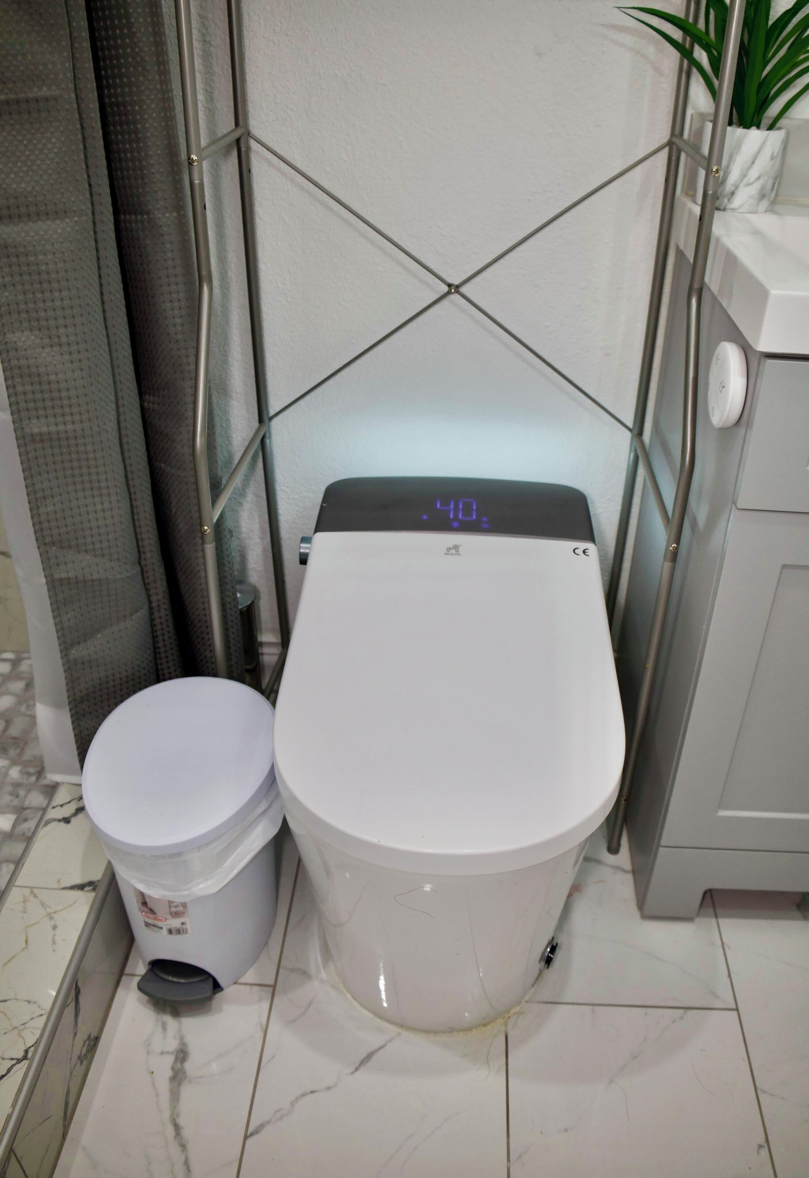Un baño con inodoro, cubo de basura y cabina de ducha.