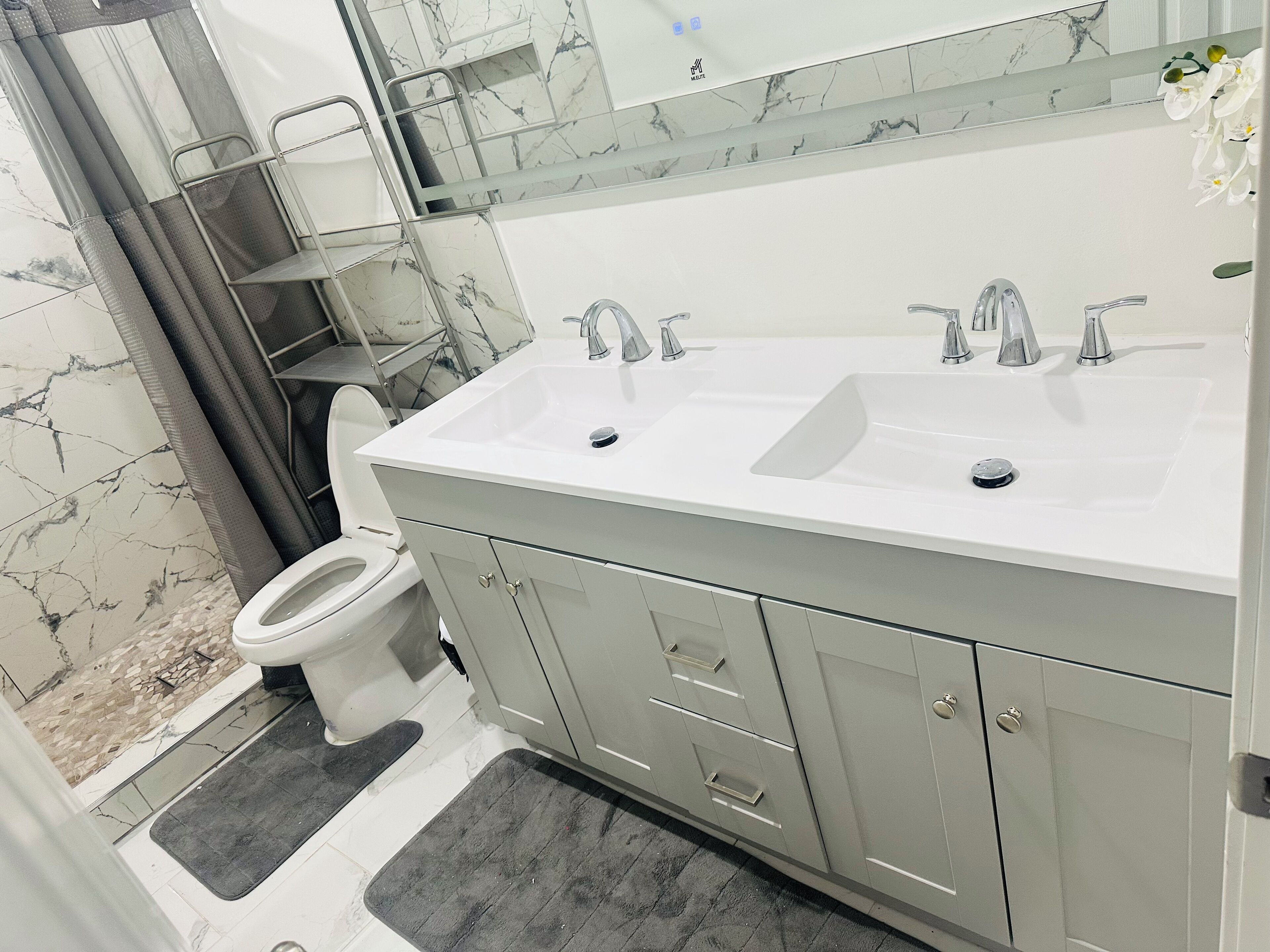 Un bany amb un lavabo blanc, dues rentapesos, un vàter i una zona de dutxa.