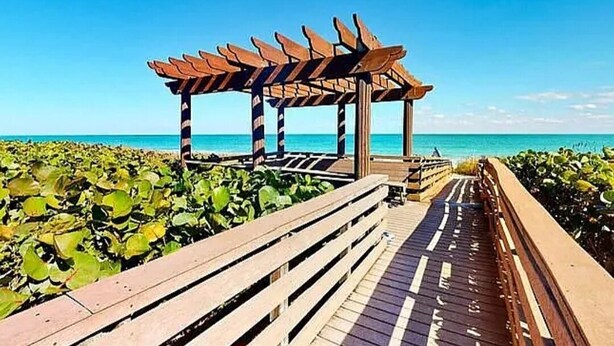 Eine Holzstege führt zu einem Pavillon mit freiem Blick auf das Meer.