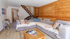 Una sala moderna con una pared de madera, una escalera y un sofá modular.
