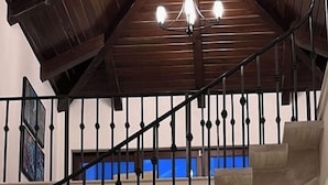 Une salle à manger spacieuse avec un plafond haut et un escalier menant à un niveau supérieur.