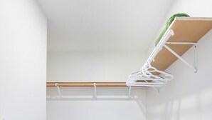 Una habitación con piso de madera, paredes blancas y un tendedero fijado al techo.
