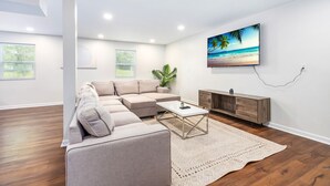 Una sala moderna con un sofá modular, una mesa de centro y un televisor montado en la pared.