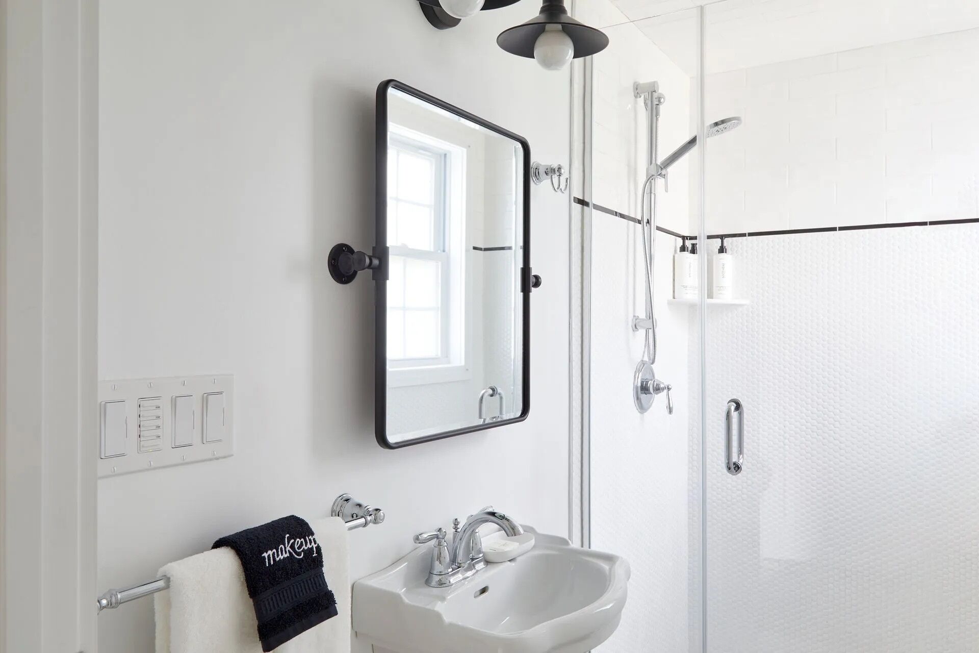 Un bagno moderno con un lavandino bianco, uno specchio grande e una cabina doccia in vetro.