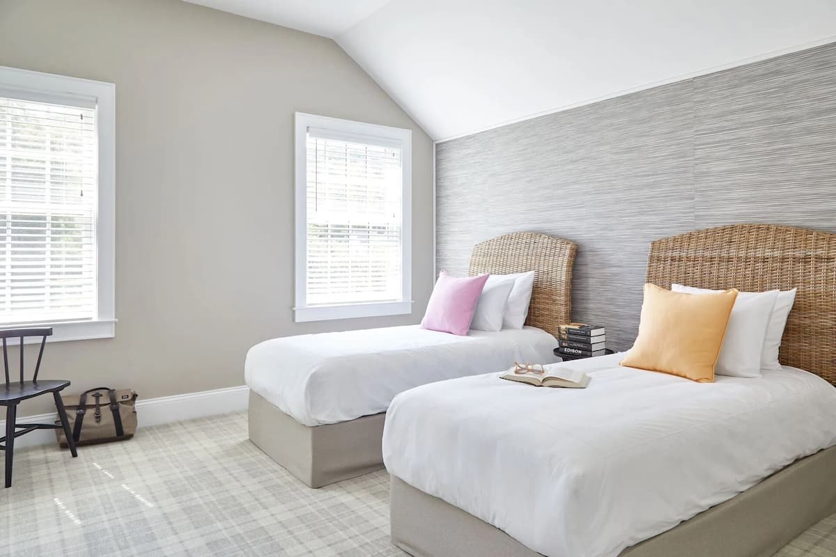 A bedroom with two beds, a small table, and a chair.