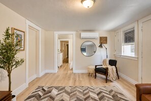 A hallway with a wooden floor, a mirror, a chair, and a potted plant. - 1BR + Office & Parking - Near Downtown SJ, Tech & Hospitals (San Jose)