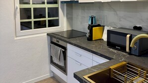 Une cuisine moderne avec des armoires blanches, un four encastré, un four à micro-ondes et une fenêtre à vitre dépolie.