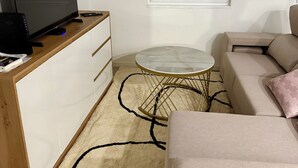 Un salon avec un téléviseur, un canapé, une table basse et une fenêtre.