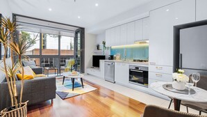 A modern kitchen with a dining area, large windows, and a cozy seating area with a sofa and coffee table.