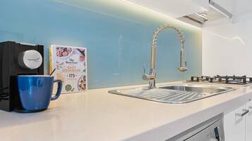 Una cocina moderna con un lavamanos de acero inoxidable, un lavavajillas Bosch y una cafetera.