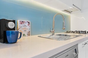 Una cuina moderna amb un vàter d'acer inoxidable, un rentaplats Bosch i una cafetera.