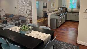 A modern kitchen with a central island, a dining area with a black table, and a living room with a patterned wall. - Convenient well appointed home near downtown Carrboro and farmers market (Carrboro)