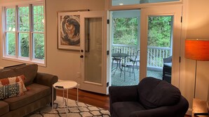 A living room with a sofa, a small table, and a chair. There is a door leading to an outdoor deck with a table and chairs. - Convenient well appointed home near downtown Carrboro and farmers market (Carrboro)
