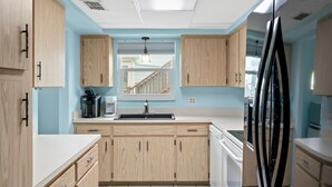 A modern kitchen with light wood cabinets, a stainless steel refrigerator, and a built-in oven. - Walk To Beach, North End Restaurants, Night Life Steps Away! (Fort Myers Beach)