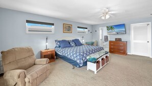 A bedroom with a bed, a chair, a dresser, a nightstand, and a ceiling fan. - Walk To Beach, North End Restaurants, Night Life Steps Away! (Fort Myers Beach)