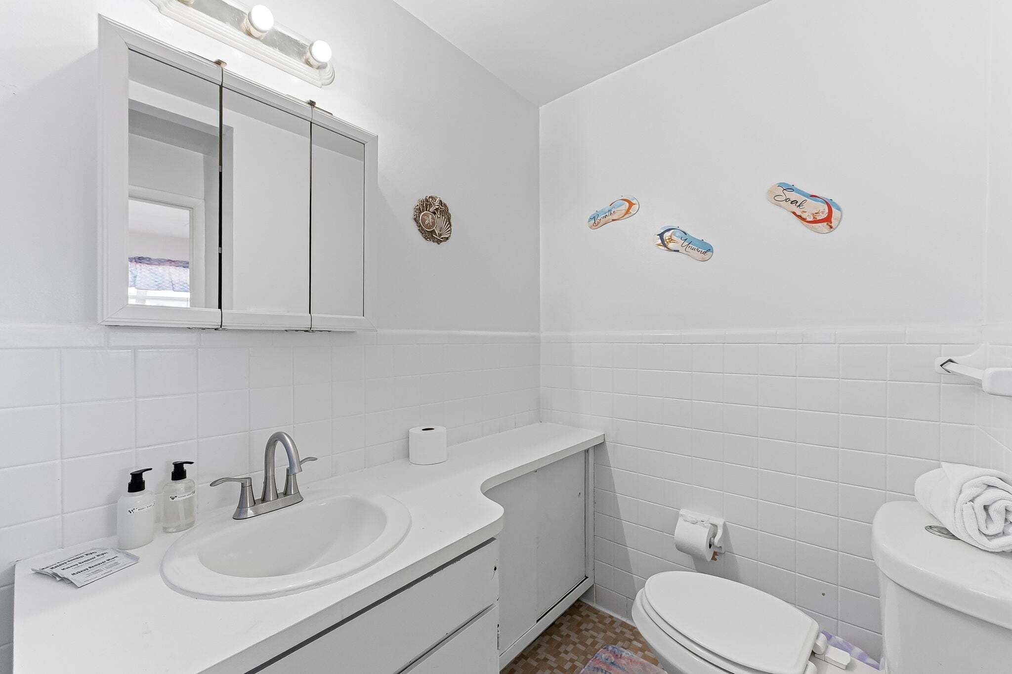 A bathroom with a white sink, mirror, and toilet, with decorative fish stickers on the wall.