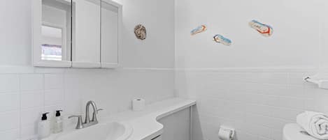 A bathroom with a white sink, mirror, and toilet, with decorative fish stickers on the wall.