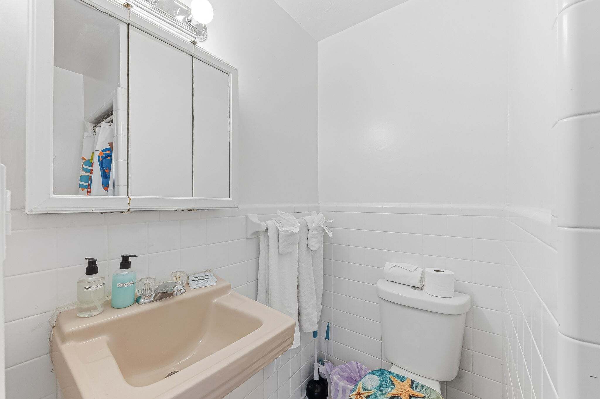 A bathroom with a sink, mirror, toilet, and a shower area.