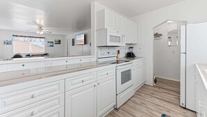 A modern kitchen with white cabinetry, a microwave, stove, and refrigerator.