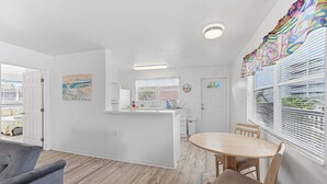 A modern kitchen with a central island, a dining area with a round table, and a living space with a sofa.