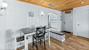 A dining area with a wooden ceiling, white walls, and a kitchen visible in the background. - Walk To Beach, North End Restaurants, Night Life Steps Away! (Fort Myers Beach)