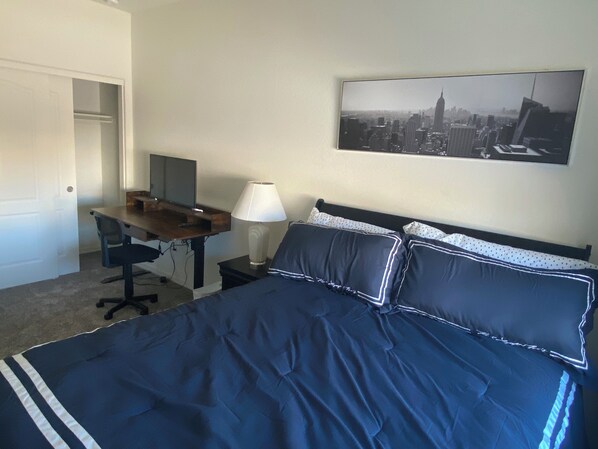 Ein Hotelzimmer mit Bett, Schreibtisch, Stuhl, Lampe und einem Stadtbild an der Wand.