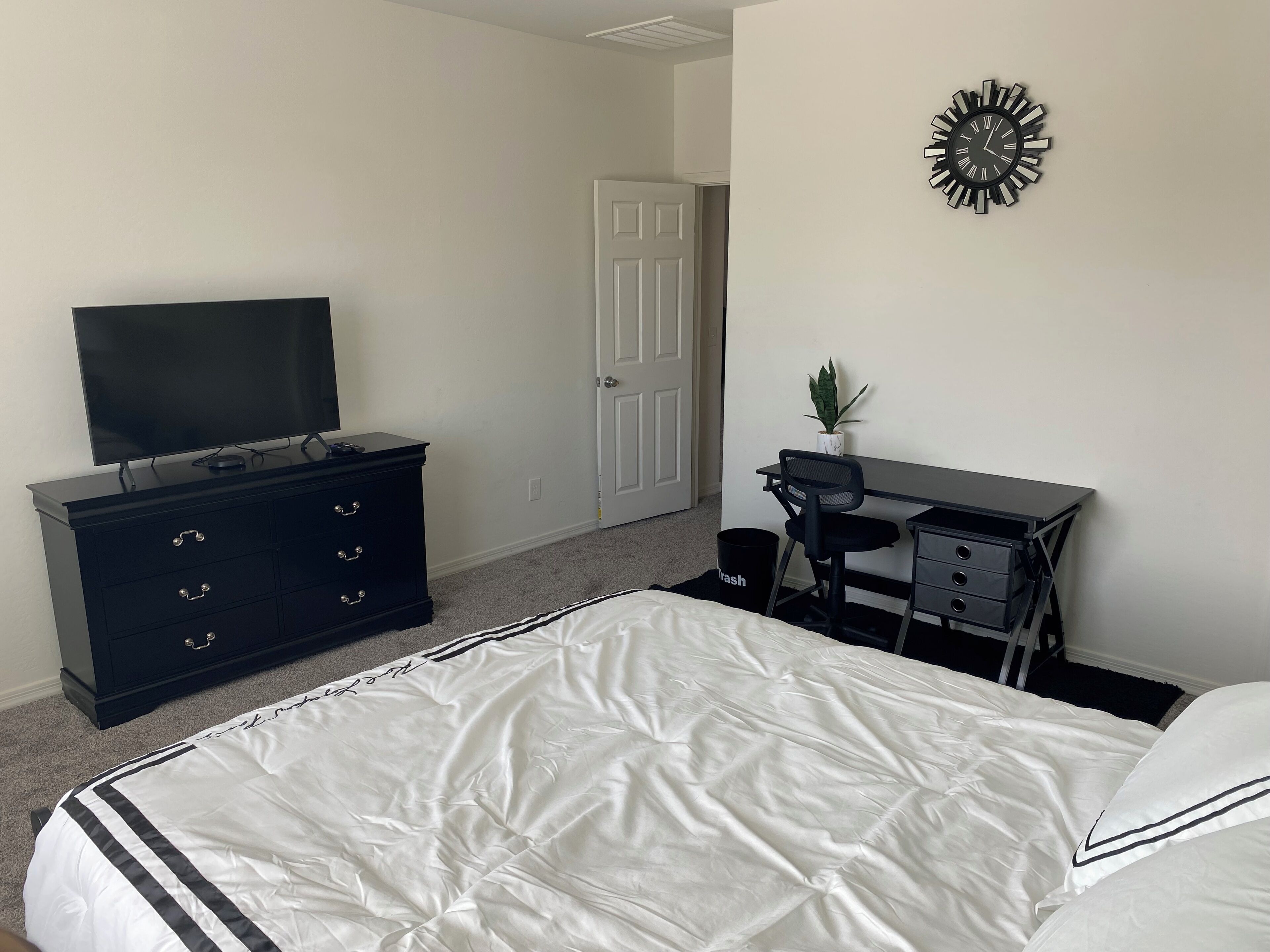 Une chambre à coucher comprenant un lit, une commode, un téléviseur, un bureau et une chaise.