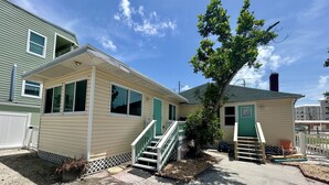 A two-story house with a front porch, a small tree, and a visible chimney. - Walk To Beach, North End Restaurants, Night Life Steps Away! (Fort Myers Beach)