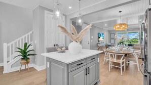 A modern kitchen with a central island, white cabinetry, and pendant lighting.